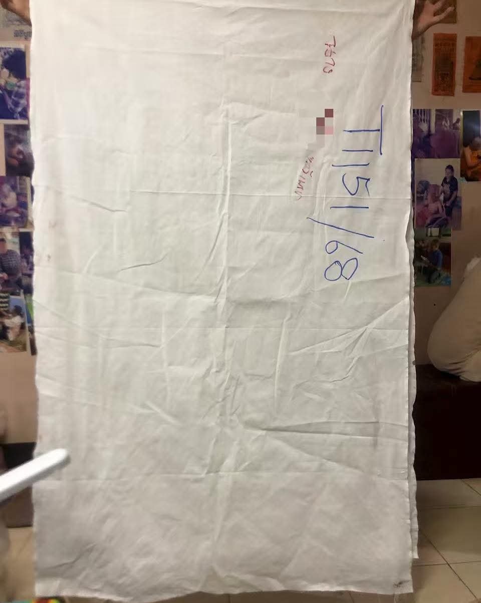 White burial shroud connected to Nong Phet Wanisa, shown as one of the direct ritual materials used for the amulets