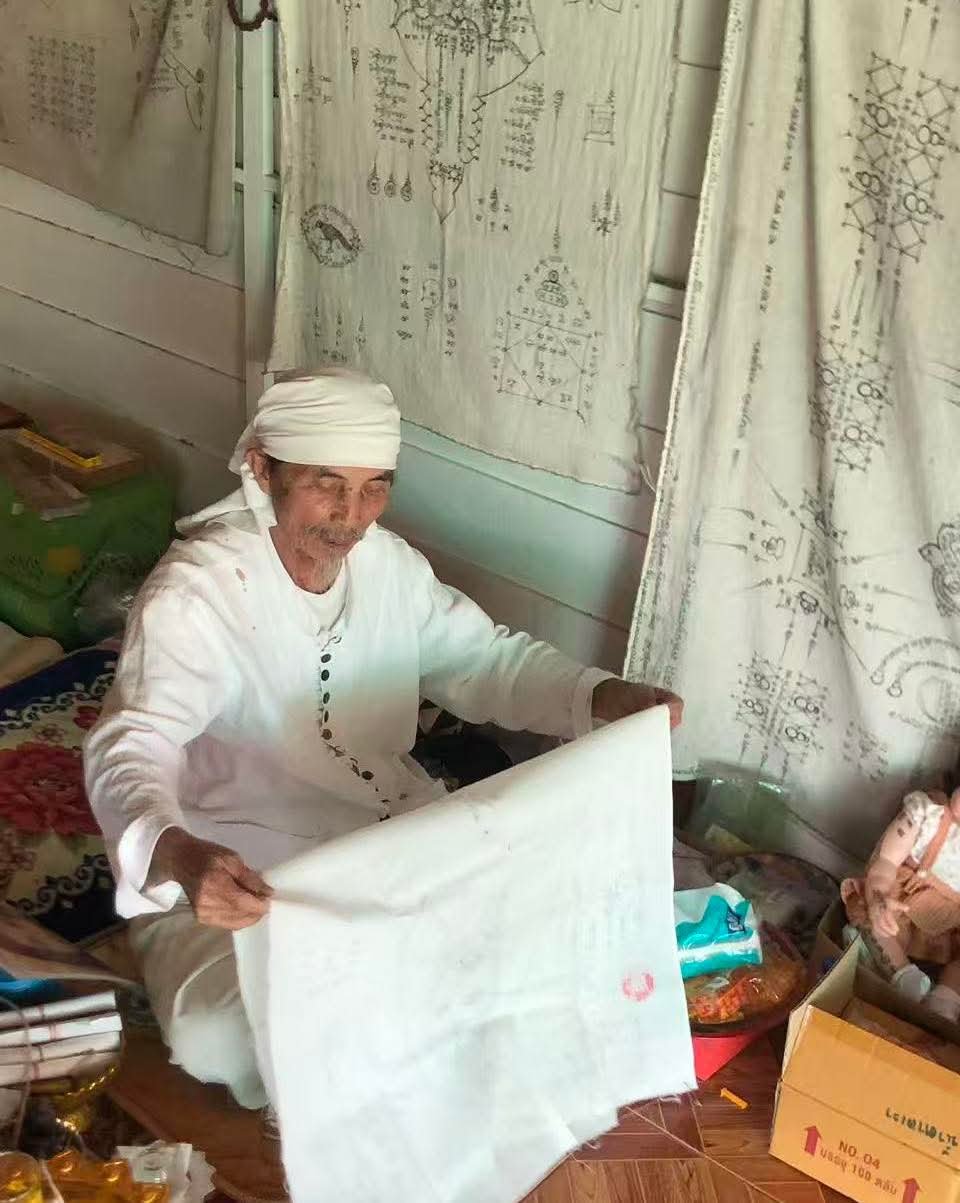 White burial shroud shown during ritual handling as one of the direct materials connected to Nong Phet Wanisa