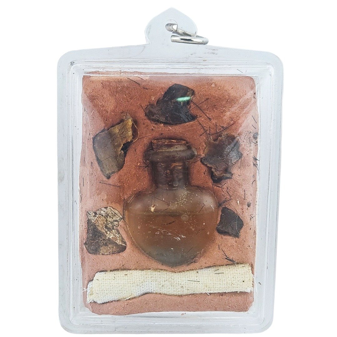 Back view of Nong Phet Wanisa locket showing sealed ritual ingredients and small oil bottle inside the casing