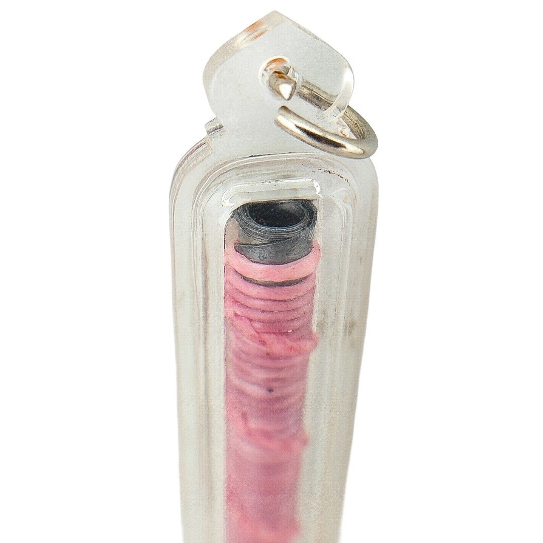 Close up of Takrut Bua Bang Bai Na Ok Tek showing hand-inscribed lead takrut inside clear protective casing