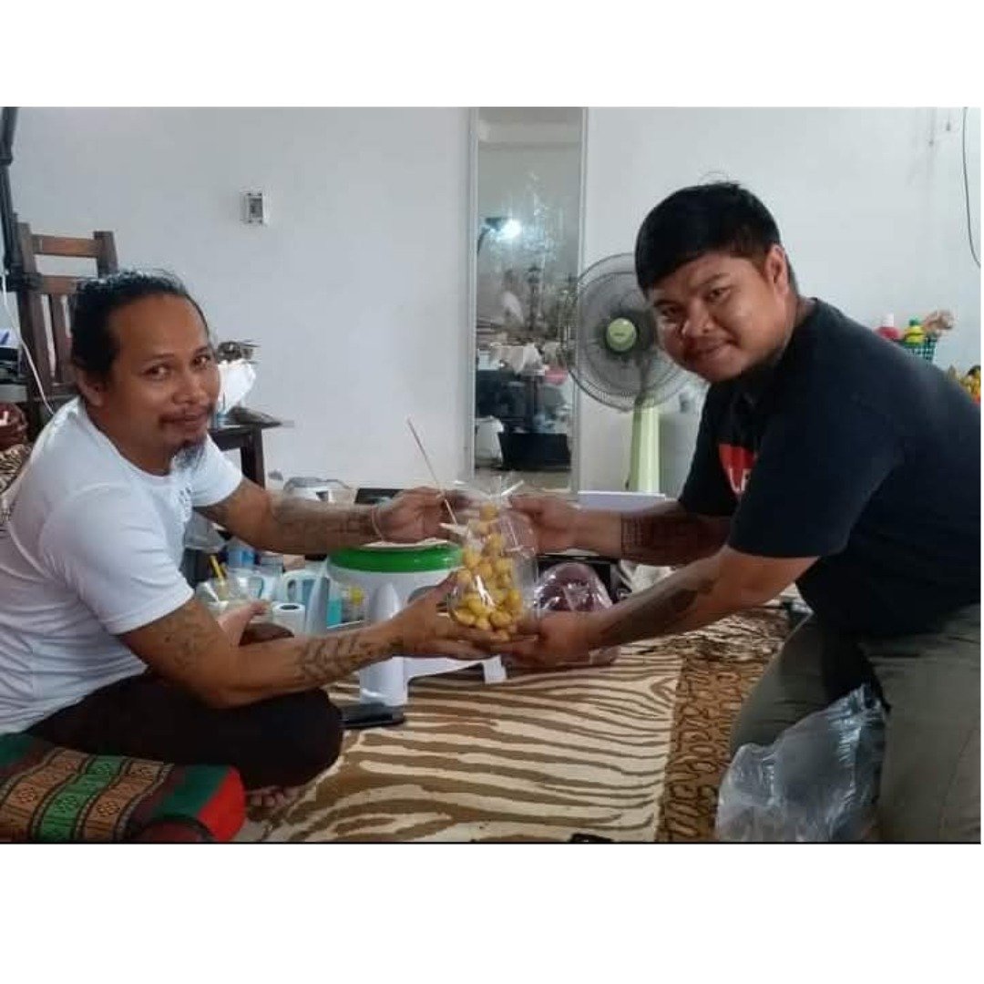 Two men holding a wrapped offering during a private meeting connected to the spiritual lineage.