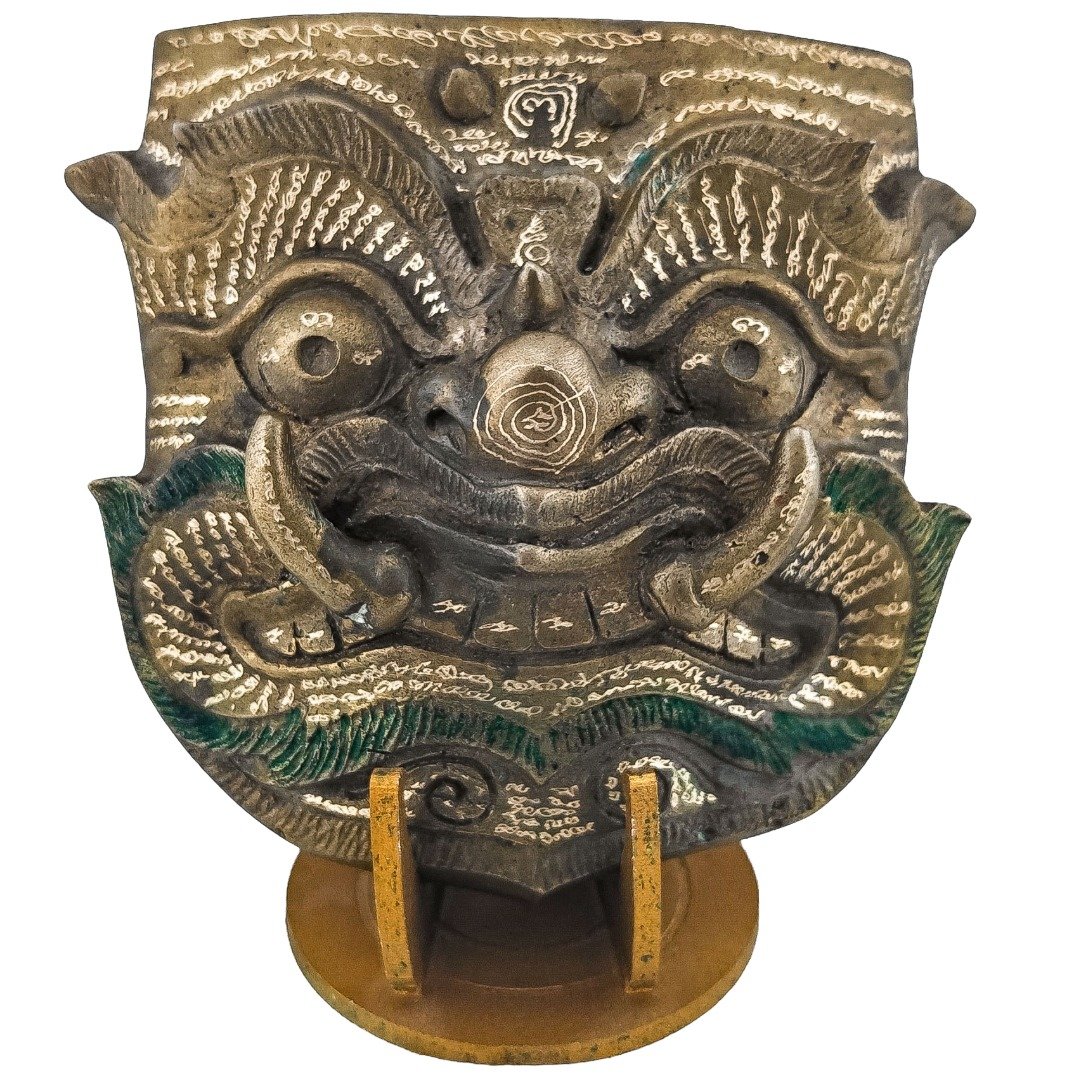 Full Phaya Purisat Phi Lu mask by Ajarn Kitkamo displayed on its stand with hand-engraved yants across the front
