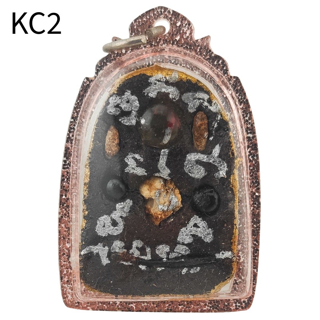 Back of the Khun Chang amulet displaying fossilized rice relic, coffin nail, gradook fragment, crystals and sacred inscription.