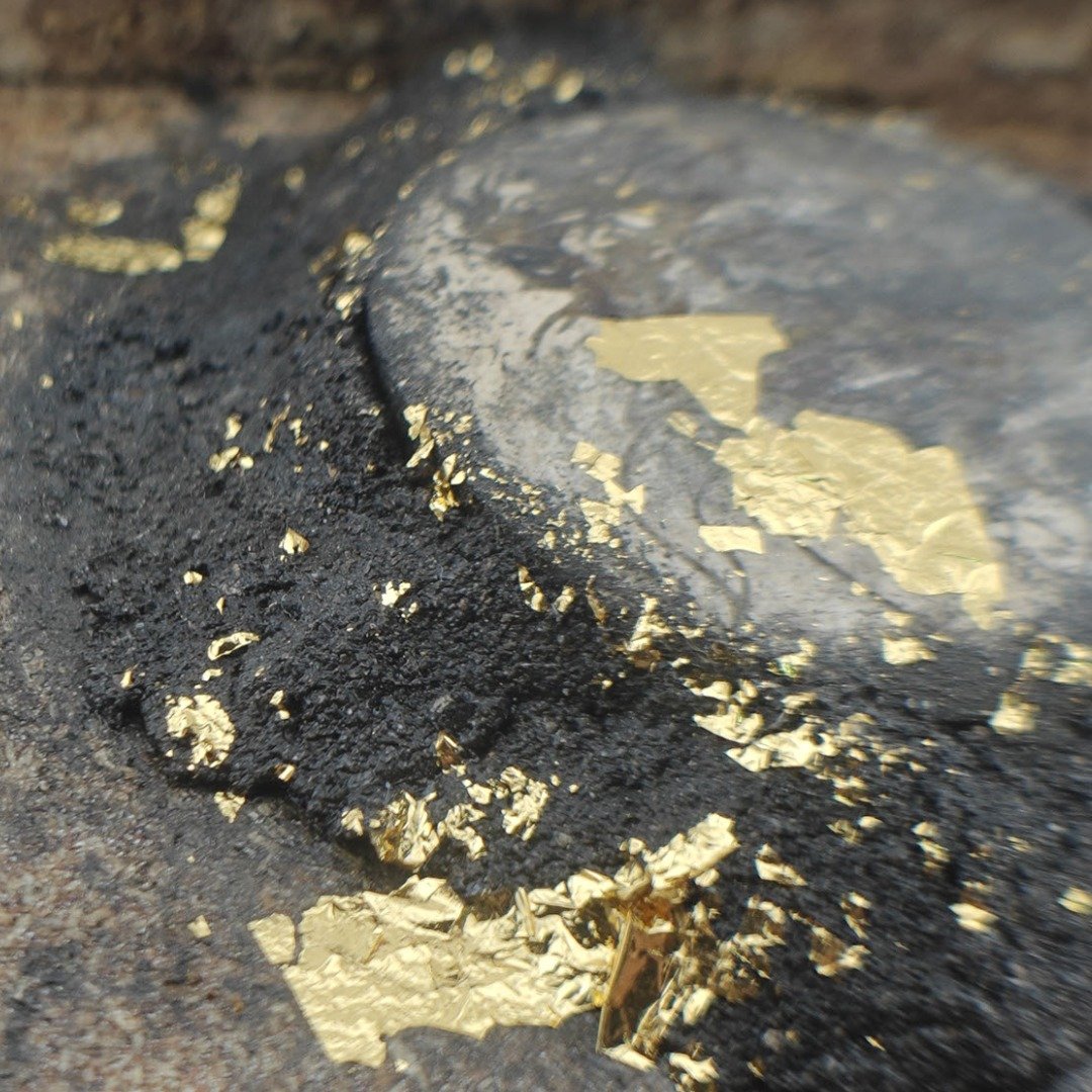 Close-up of cremation sludge, gold leaf and specially selected prai panneng on the back of Ajarn Tomβs Phaya Yom coffin wood Mai Yant.