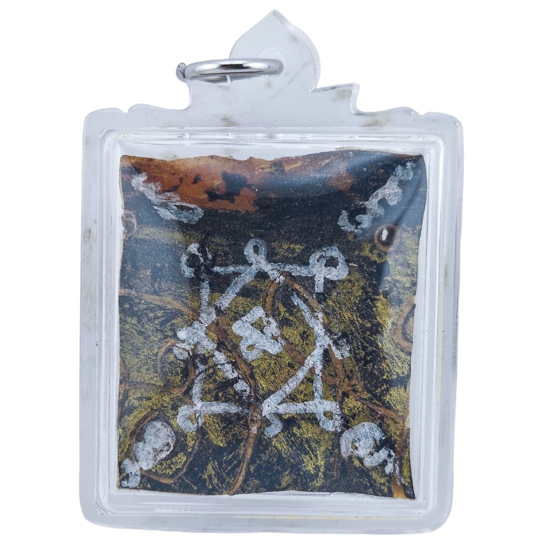 Prai John Wicca thief spirit amulet featuring white hand-drawn yant inscriptions on a dark surface, enclosed in a clear protective casing.
