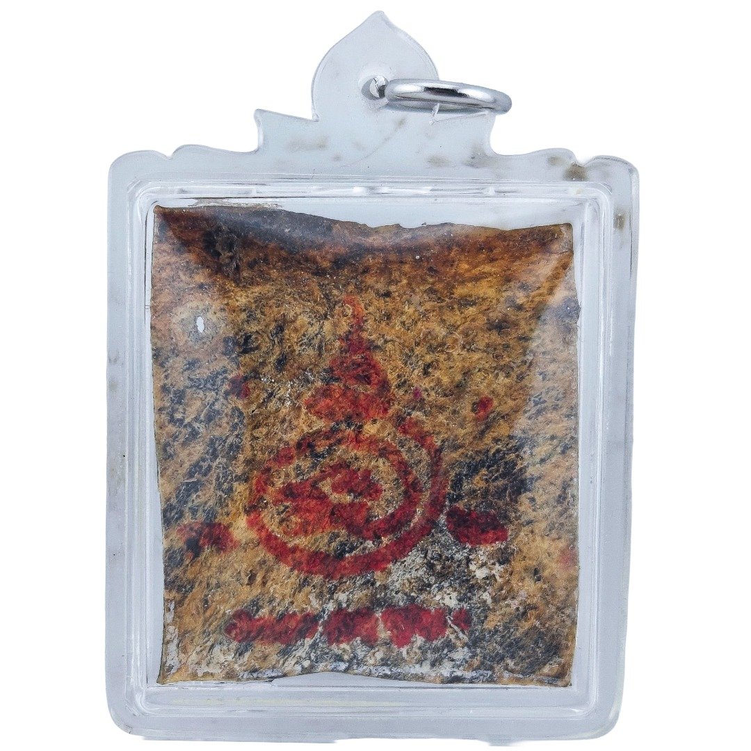 Prai John Wicca by Ajarn Kitkamo BE 2569, showing red and black ritual markings on the amulet inside a clear casing.