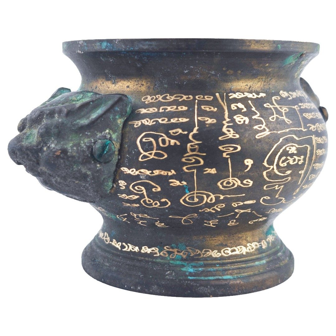 Close-up of sacred symbols and inscriptions across the darkened samrit body beside one handle