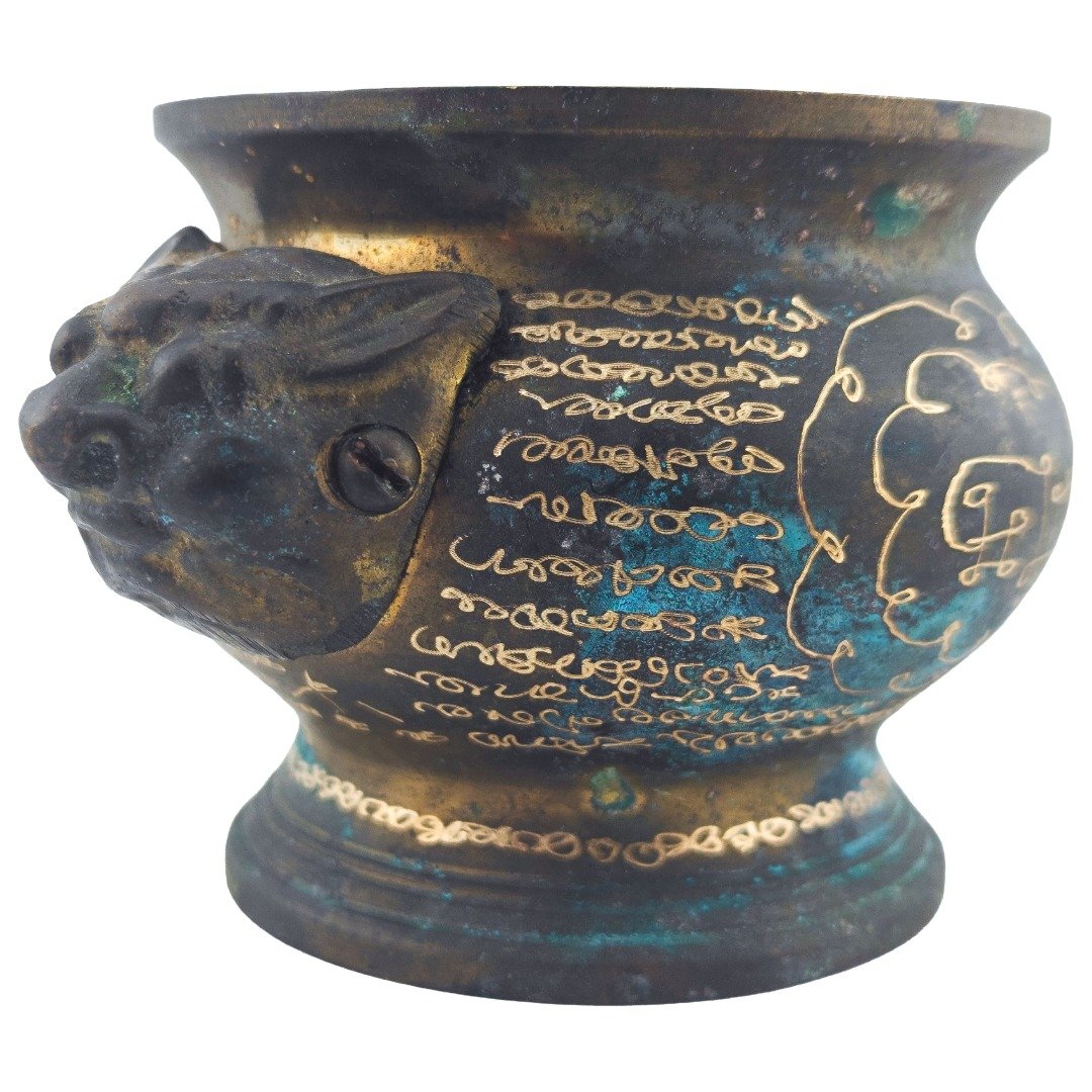 Handle Side close-up of the old samrit incense urn showing sacred inscriptions, aged patina and an animal-head handle