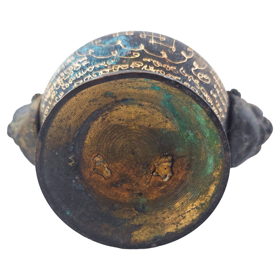 Underside of the old samrit incense urn showing circular finishing marks, darkened metal and green oxidation