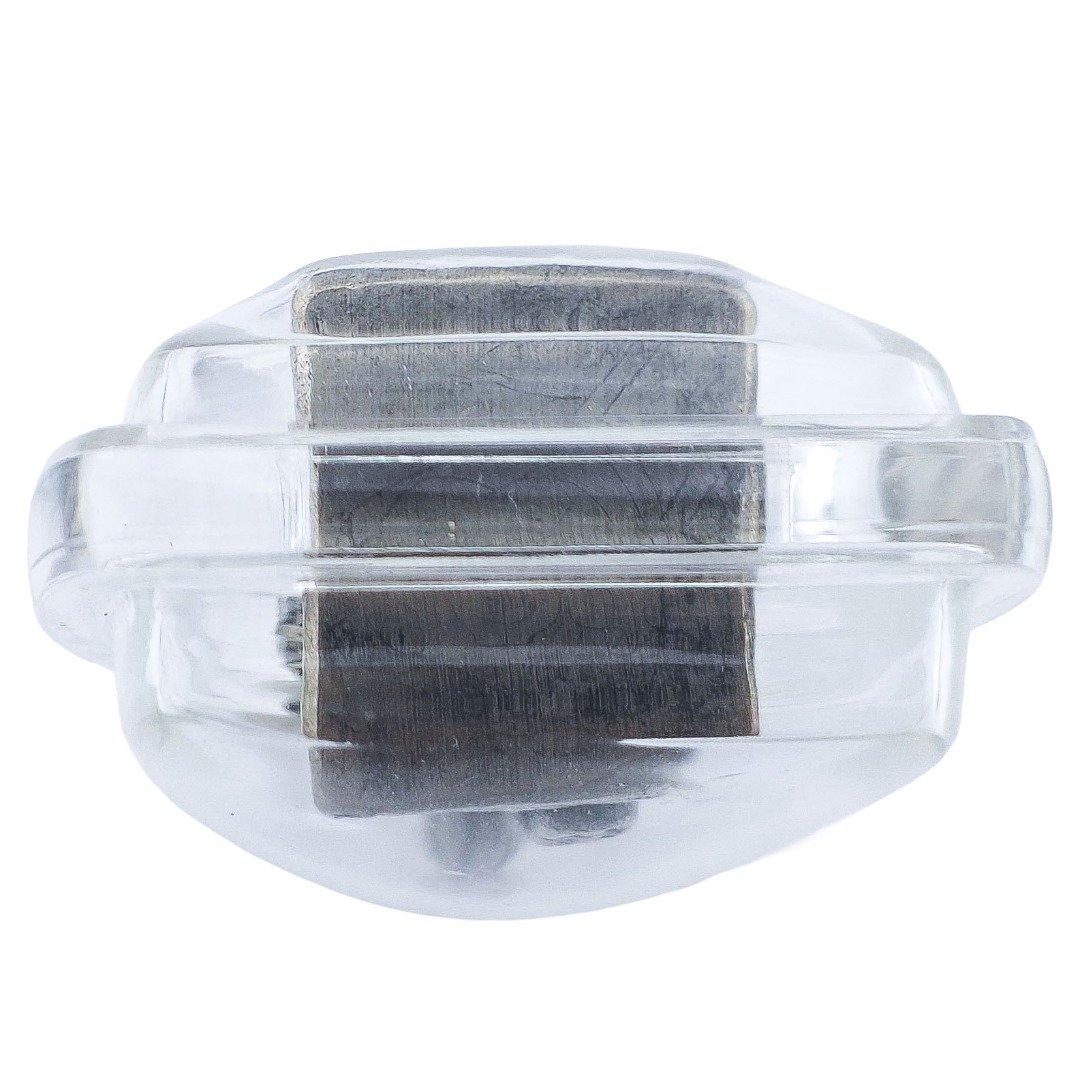Underside of Forgotten Nang Kwak showing the darkened metal base and visible finishing marks through the transparent casing.