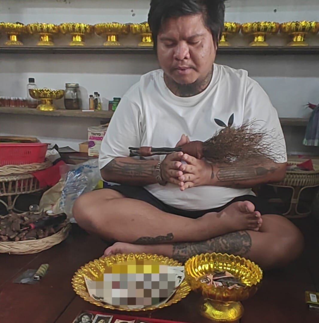Ajarn Kitkamo seated with ritual offerings during a blessing session for the one-to-one Nameless Monk Prai amulet.