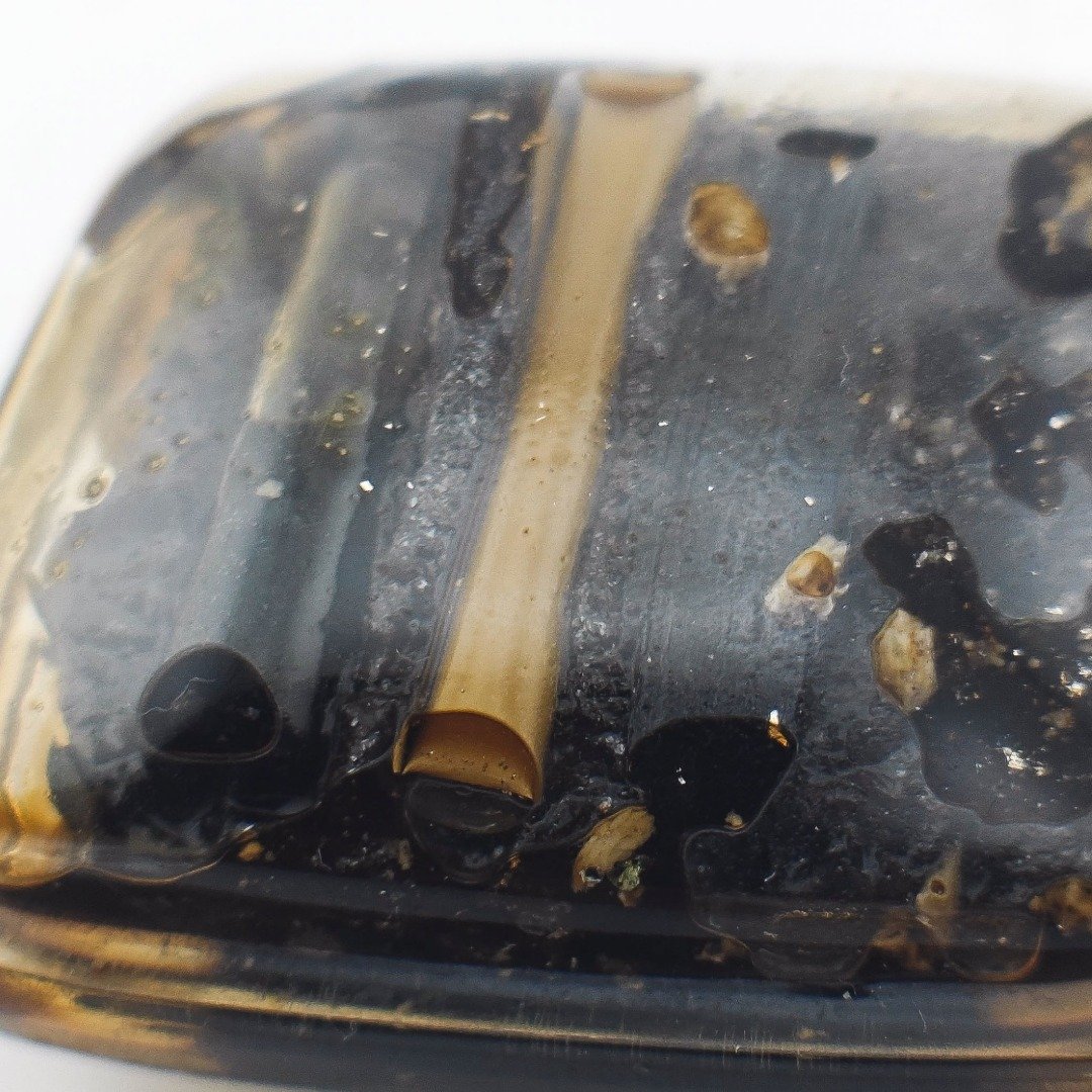 Close-up of Panneng Ngan rear casing showing a takrut, dark prai murn sarn and small embedded fragments.