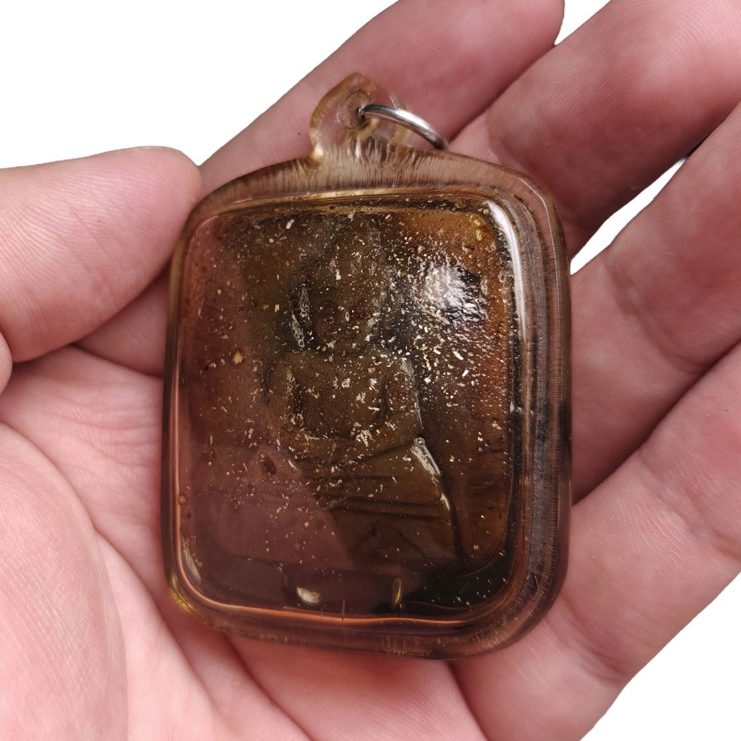 Angled front view of Ajarn Tay's old Panneng Ngan showing the carved figure, embedded particles and aged casing.