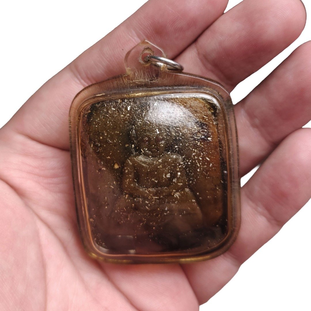 Ajarn Tay Panneng Ngan front showing the carved panneng figure beneath the dark amber casing, held in hand.