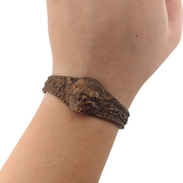 Phra Pirab Samrit bracelet by Ajarn Wut worn on the wrist, showing the fierce deity face and ornate bronze-coloured design.