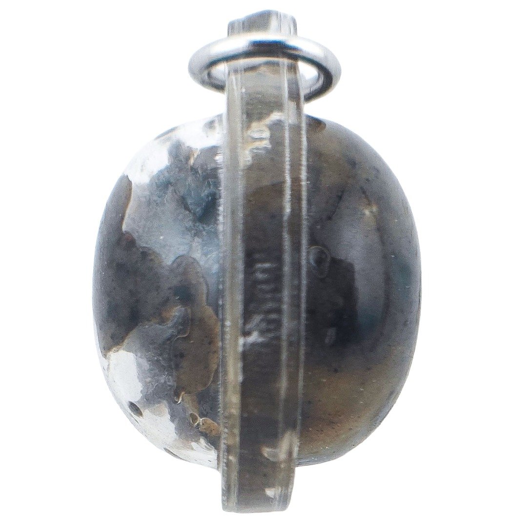 Side profile of a Pure Hakom Wax Luk Om showing the thickness of the dark wax amulet, transparent casing and metal hanging ring.