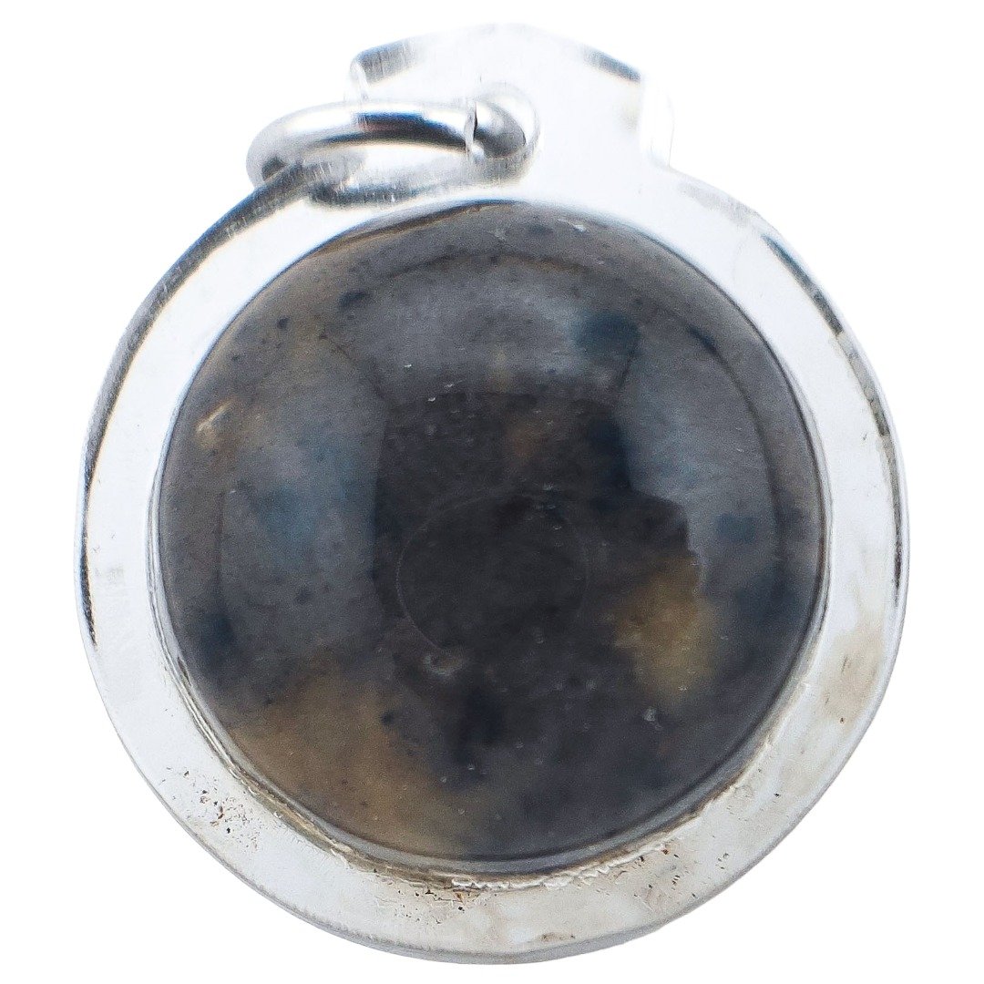 Reverse close-up of a Pure Hakom Wax Luk Om by Ajarn Tom, showing the dark wax surface through its transparent round casing.