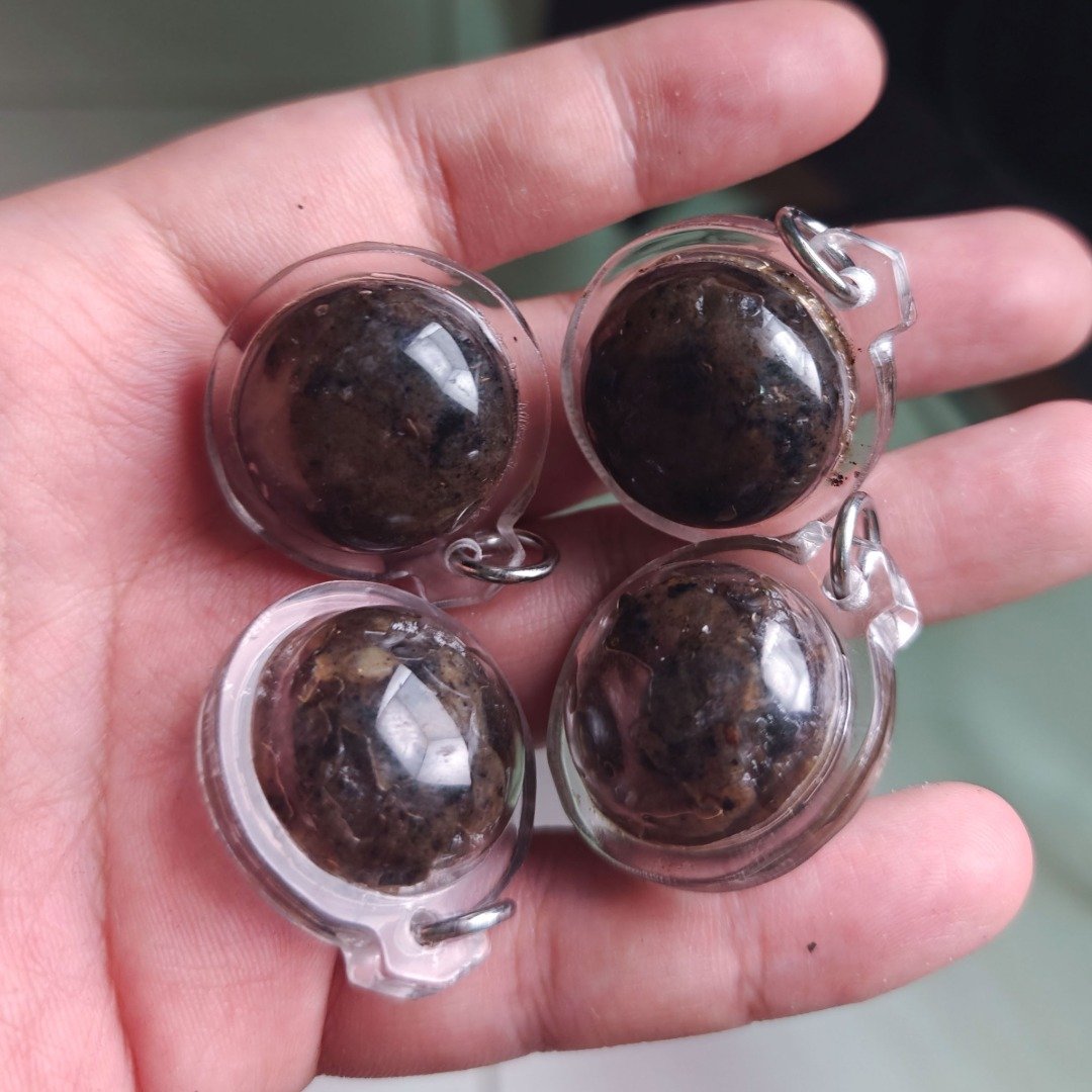 Four Pure Hakom Wax Luk Om by Ajarn Tom, showing dark concentrated Hua Chuea wax inside clear round pendant casings.