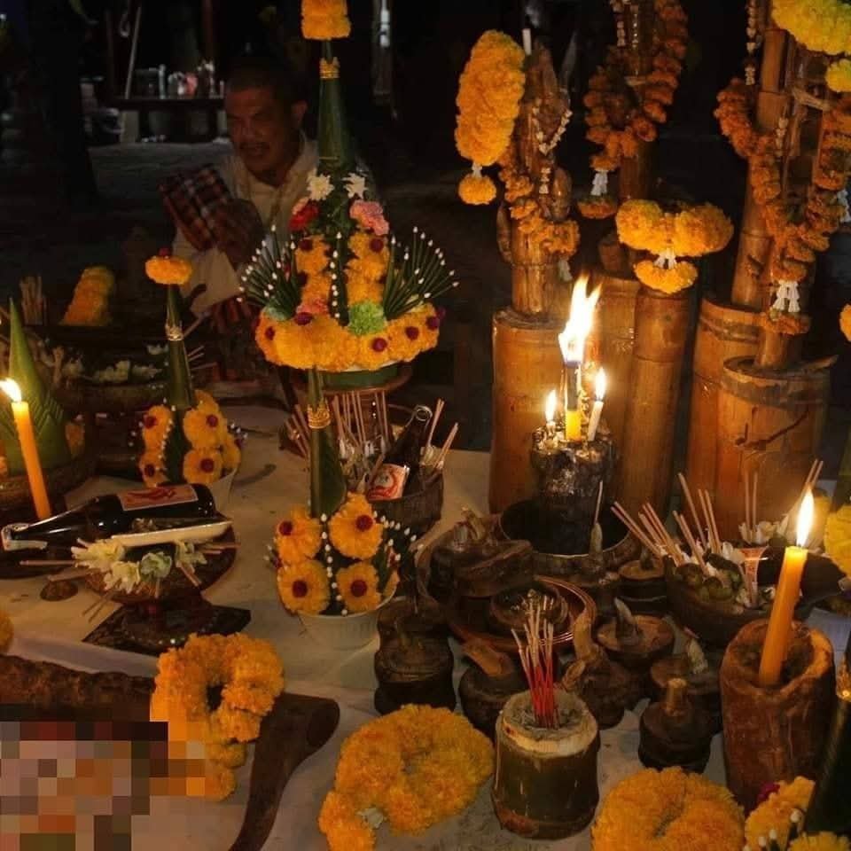 Traditional Hakom blessing ceremony with a practitioner seated behind an altar filled with candles, incense, offerings and ritual objects.