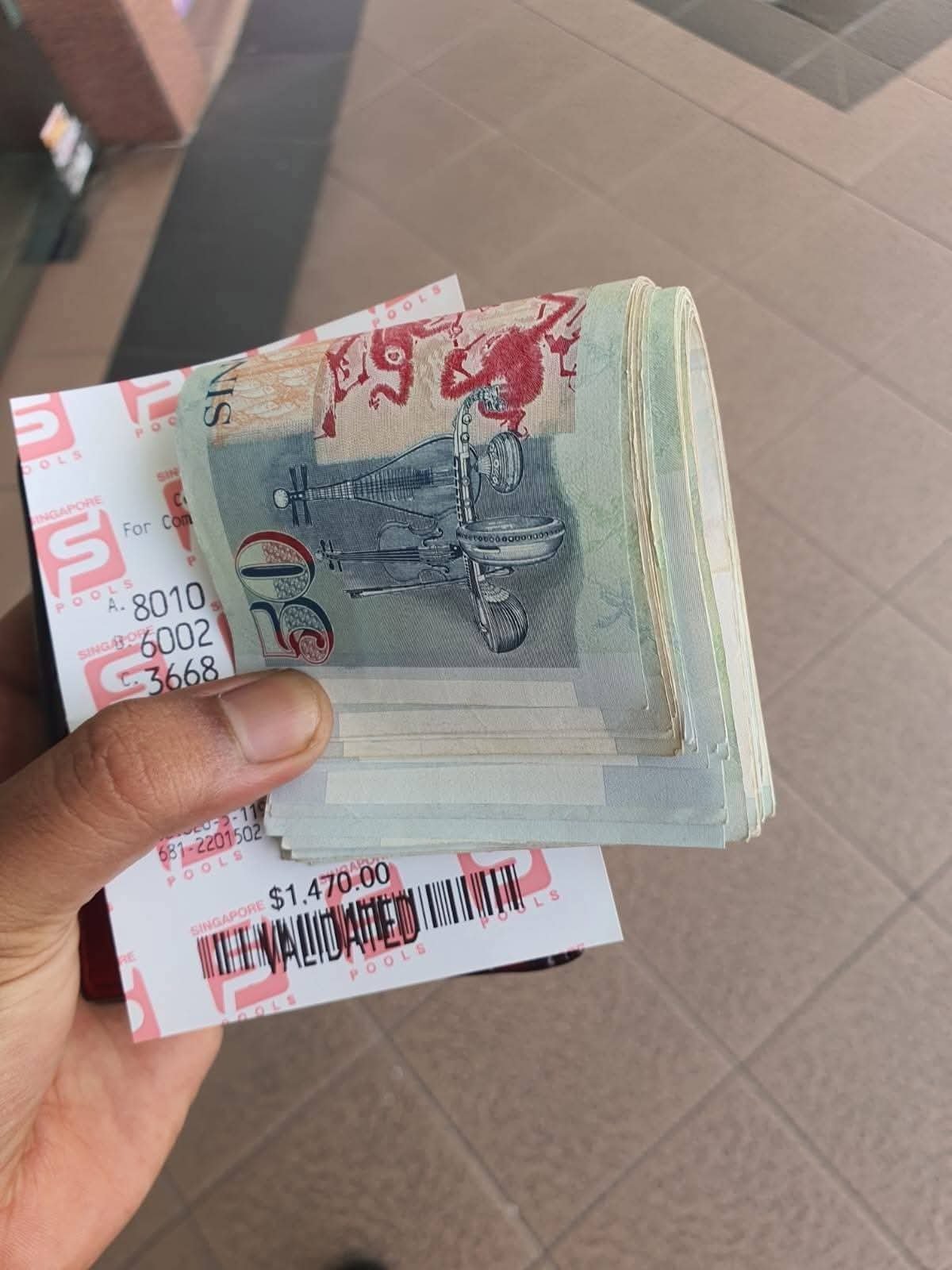 Photograph of Singapore 4D lottery tickets and cash shared as part of a customer's reported Hakom wealth and gambling luck experience.