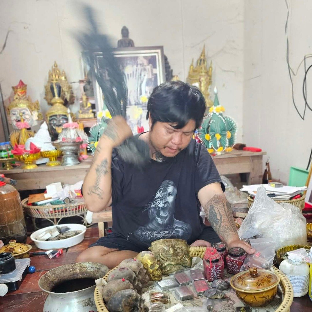 Ajarn Kitkamo swinging his Prai Command Whip during a blessing session involving multiple amulets and ritual items.