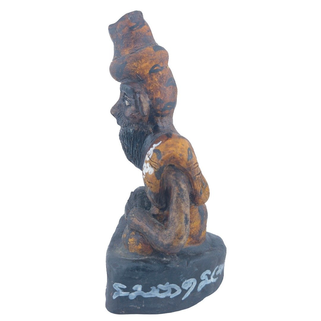 Left side view of Ajarn Tom's old Lersi Sermingpai Bucha showing the seated human-form ascetic, shoulder ornament, beard and weathered base.