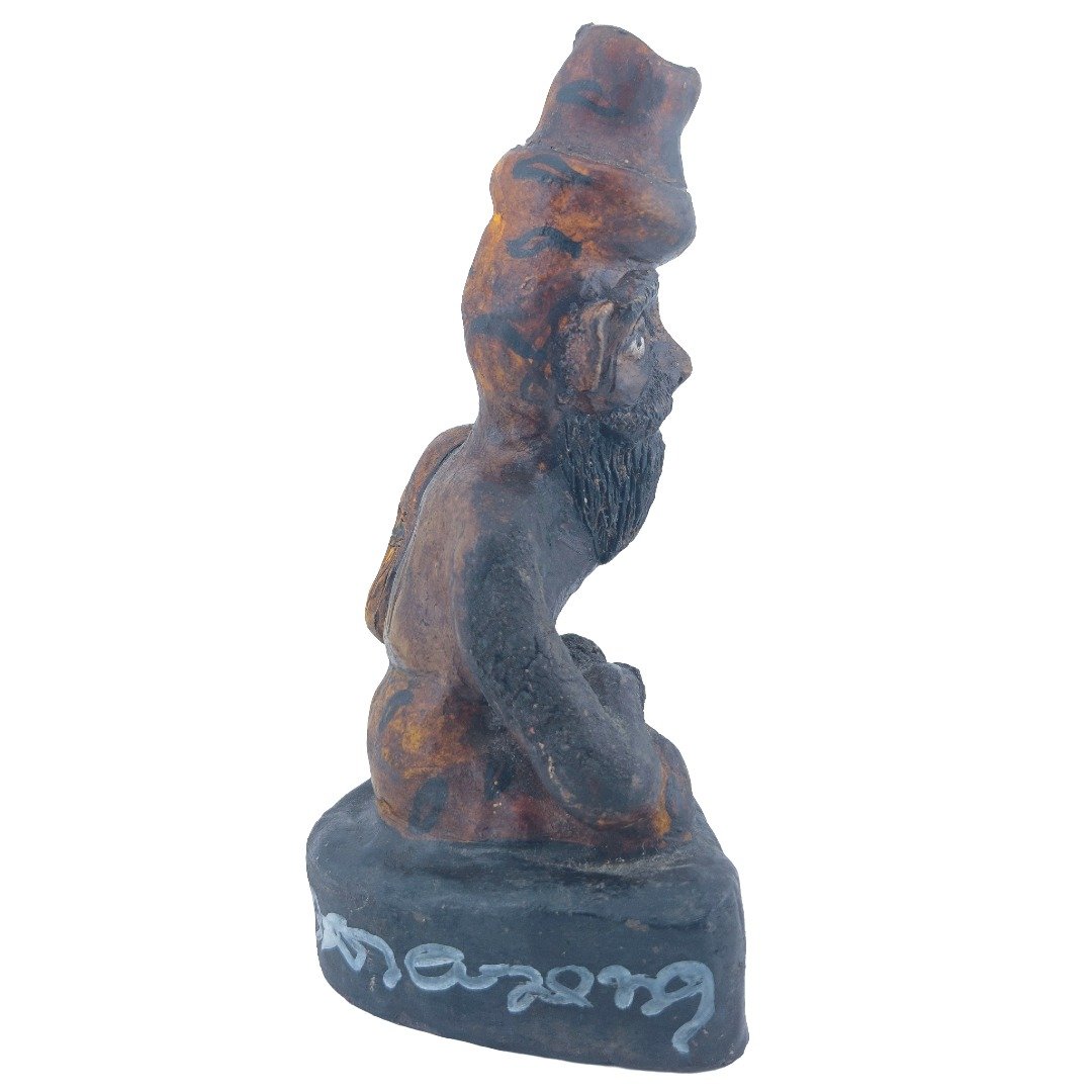 Right side view of Ajarn Tom's old Lersi Sermingpai Bucha showing the seated ascetic, long beard, weathered surface and inscribed base.