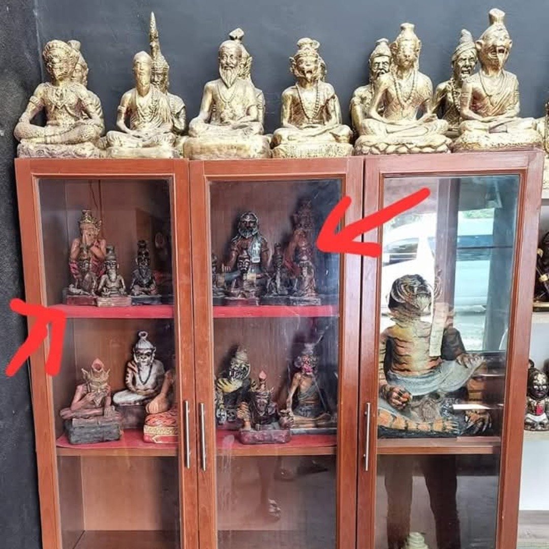 Old Lersi Buchas from Ajarn Tom's personal Samnak collection displayed in a wooden cabinet, with red arrows highlighting selected pieces.